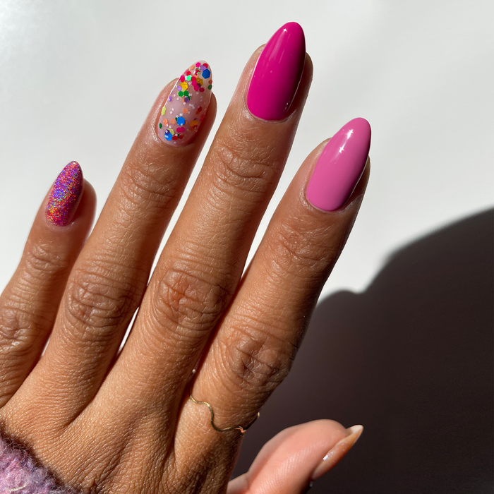 Ninth Street confetti glitter accent nails with a magenta manicure on a medium skin tone