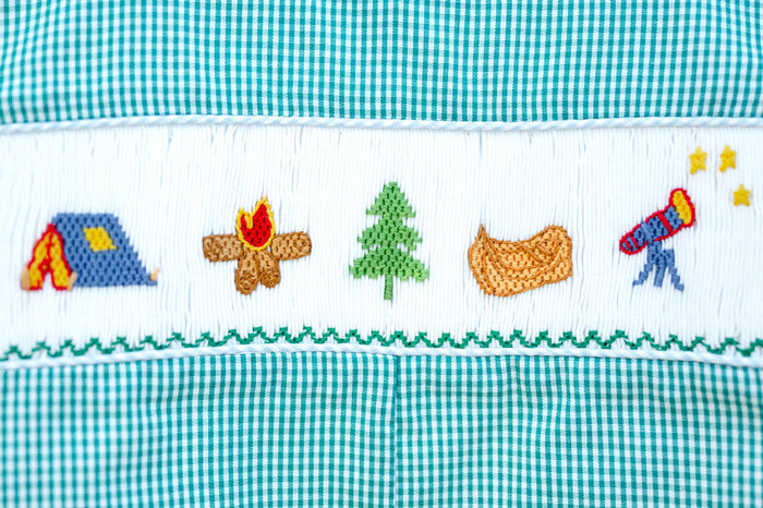 Close-up of smocked camping embroidery detail on Ruth and Ralph teal gingham Bubble, featuring tent, campfire, tree, and canoe