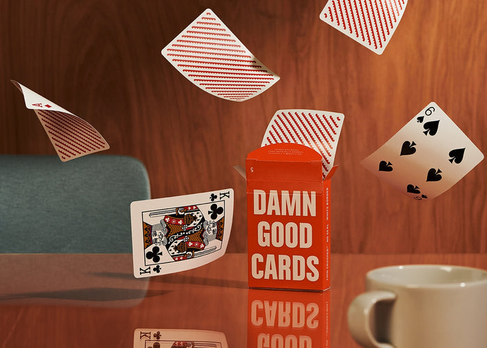 Orange playing card deck box with several scattered cards on a tabletop