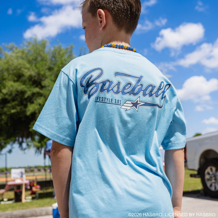 Back view of youth male model wearing light blue GI Joe tee showing Baseball Lifestyle 101 script graphic at outdoor event