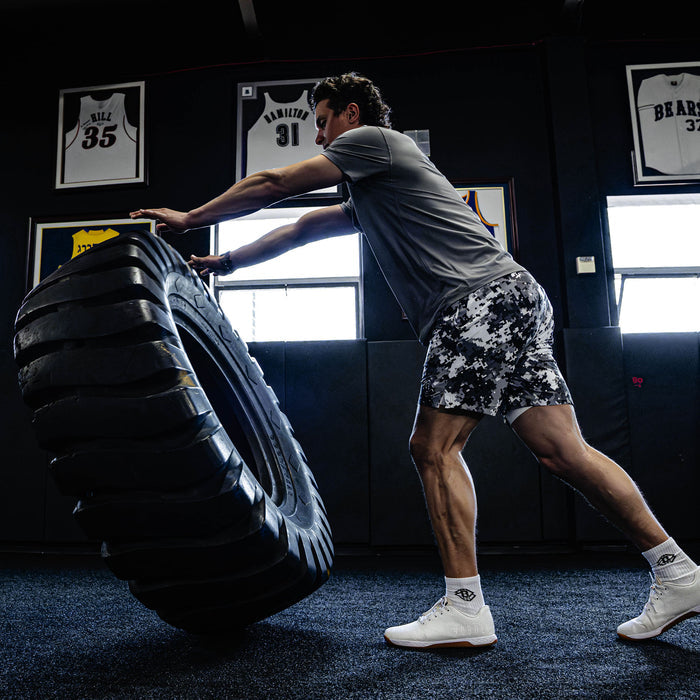 Person lifting a large tire in a gym setting.