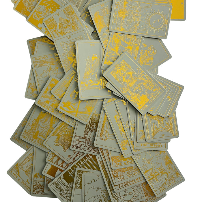 Gold-foil tarot cards scattered in a pile, showing ornate figures and titles