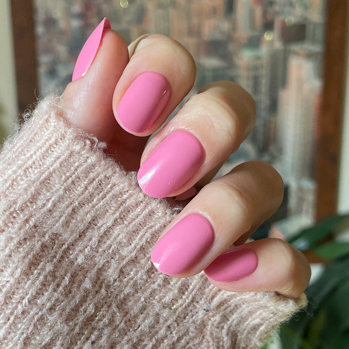 Taffy | Short | Round - Tab Press-On showing smooth glossy hot pink press-on nails on hand with cozy sweater background