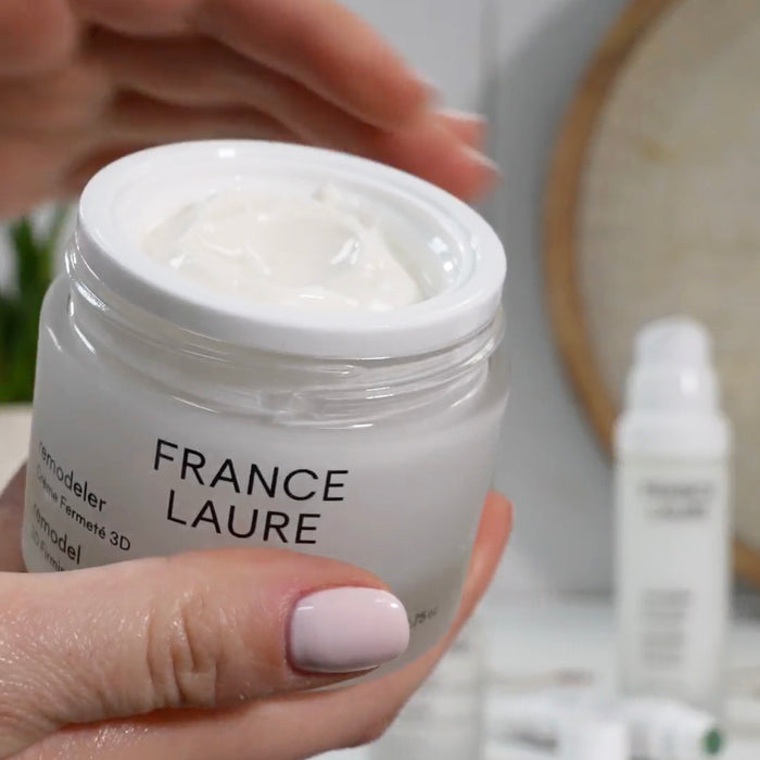 France Laure Remodeler 3D Firming Cream in open jar, showing rich white texture, held in hand with soft pink nails