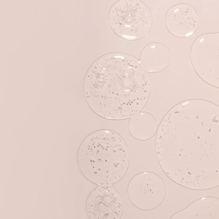 Clear skincare serum droplets with microbubbles on soft pink background, showcasing lightweight hydrating texture for all skin types