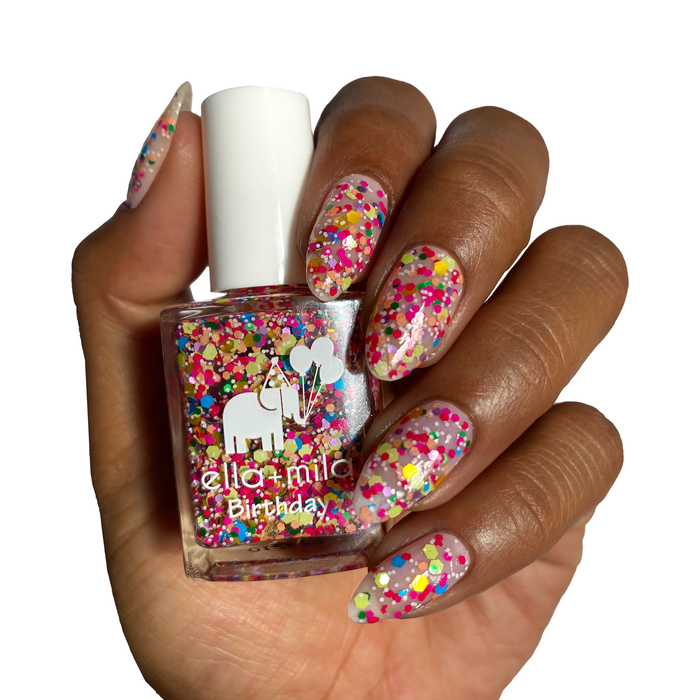 Ninth Street confetti glitter nail polish on a deep skin tone, hand holding the bottle