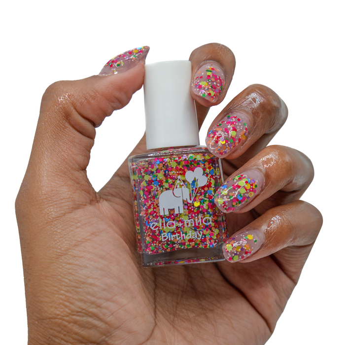 Ninth Street colorful confetti nail polish on a medium skin tone, holding the bottle