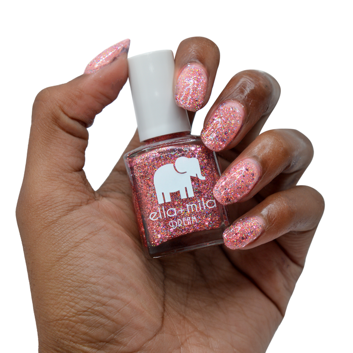 After Party rose gold glitter nail polish on a deep skin tone, hand holding the bottle