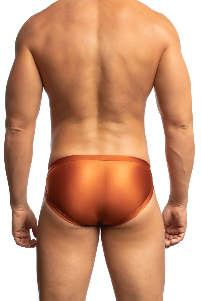 Man wearing a pair of Jack Adams copper Apollo Swim Briefs (back view) standing before a white background.