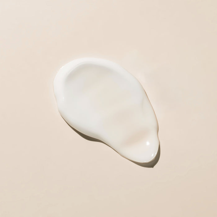Smooth white cream swatch on neutral background, showcasing rich texture for all skin types and ages