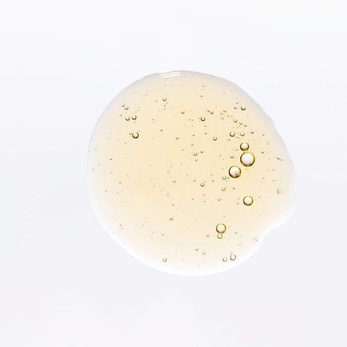 Close-up of golden skincare serum with delicate bubbles, showcasing lightweight texture for all skin types.