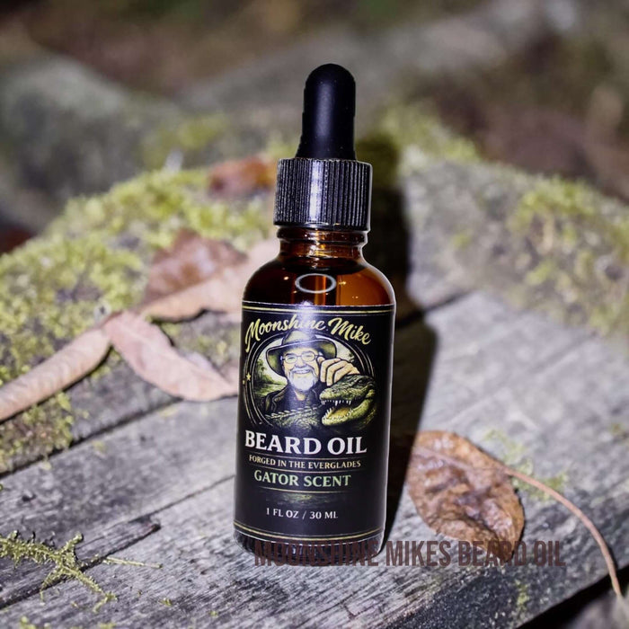Fort Denaud Beard and Skin Gator Scent beard oil in a 30ml amber glass dropper bottle on a mossy wooden surface.