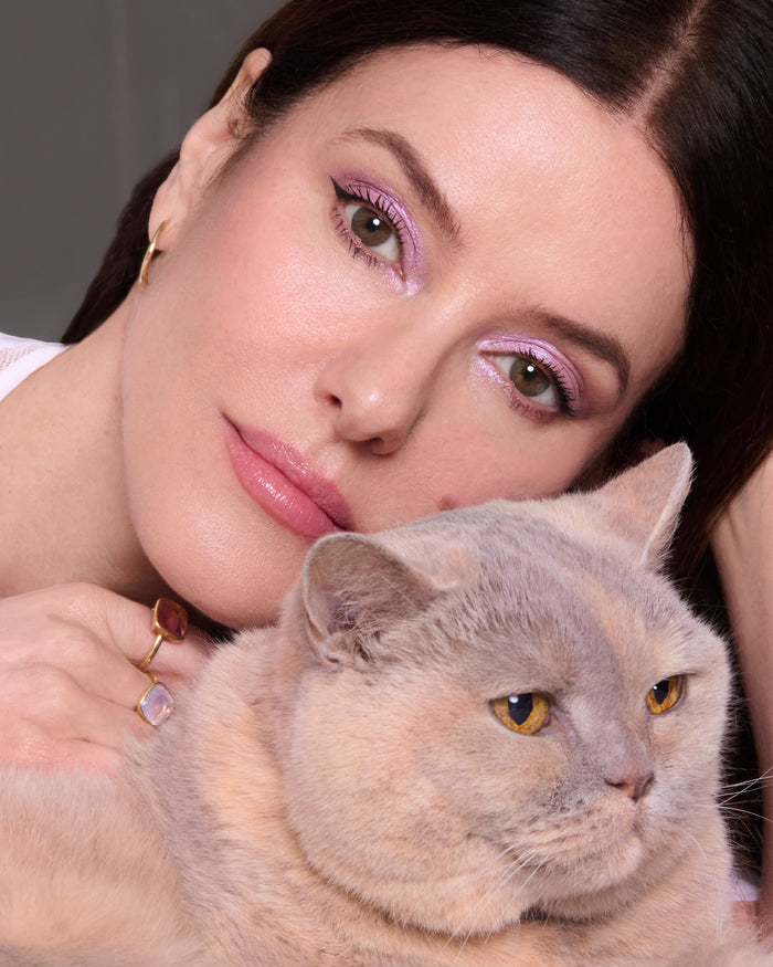 Lisa with her cat, Betty, wearing pink eyeshadow from the Betty Palette, and earrings, against a neutral background
