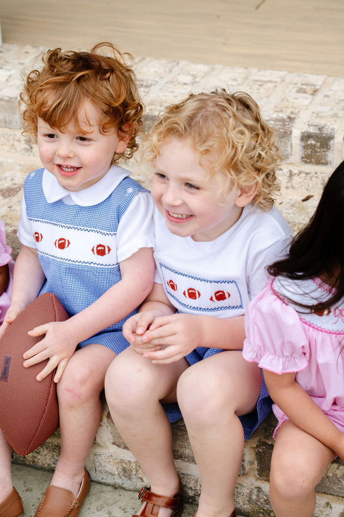 Smocked Football Shirt and Short Set with three hand-smocked footballs on a white tee and blue gingham shorts