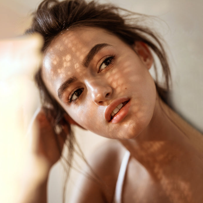 Radiant woman with glowing skin and soft natural makeup, showcasing healthy complexion and subtle sunlit texture.