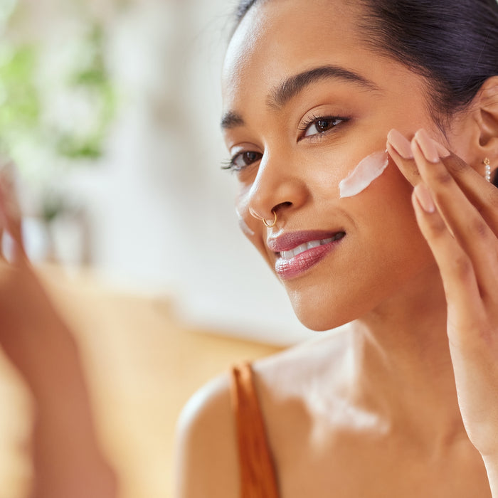 Woman gently applying moisturizing face cream to cheek, showcasing smooth skin texture and daily skincare routine
