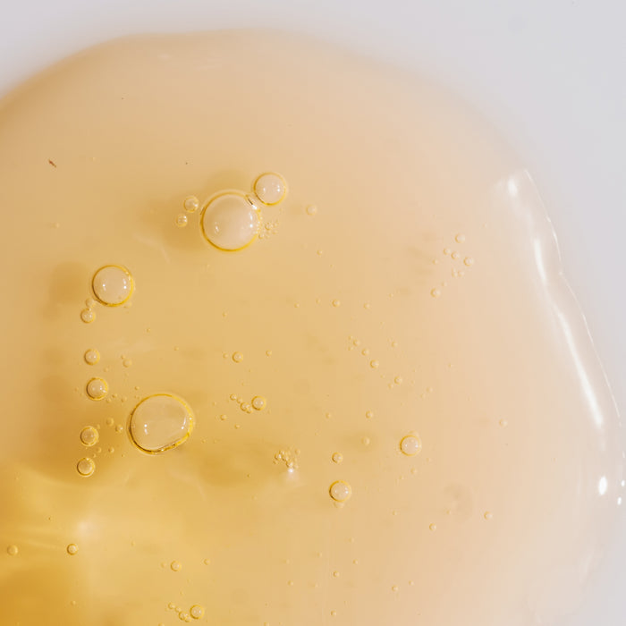 Close-up of golden skincare serum with delicate bubbles, showcasing lightweight texture for all skin types