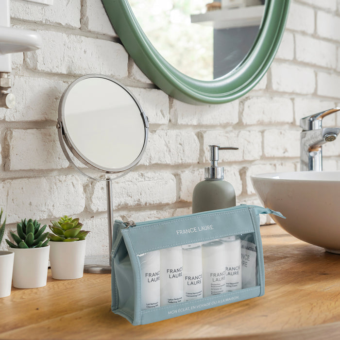 France Laure travel skincare set with cleansing milk, toner, and cream in a light blue pouch on a bathroom vanity