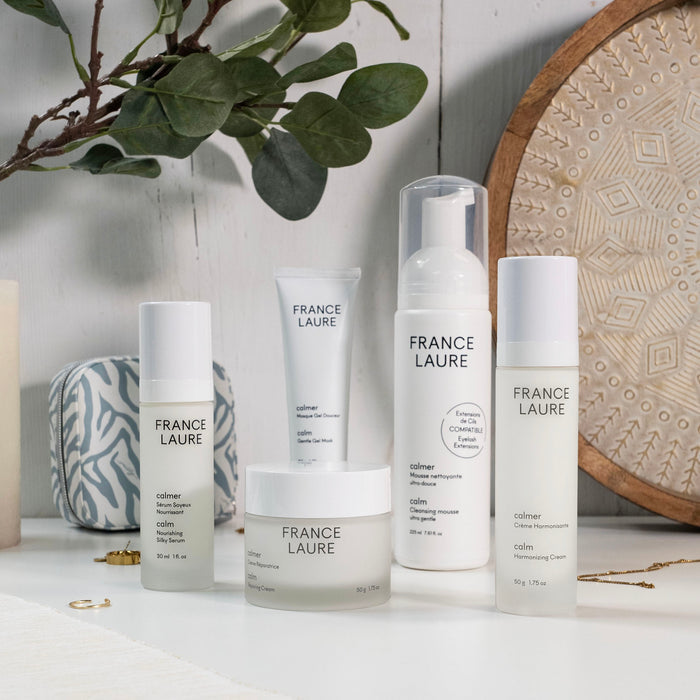 France Laure Calm skincare collection featuring nourishing serum, repairing cream, gentle gel mask, and ultra-gentle cleansing mousse on white surface with greenery