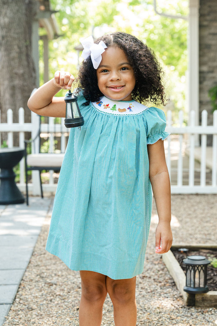 Girl standing outdoors wearing Smocked Camping Dress by Ruth and Ralph with white hair bow