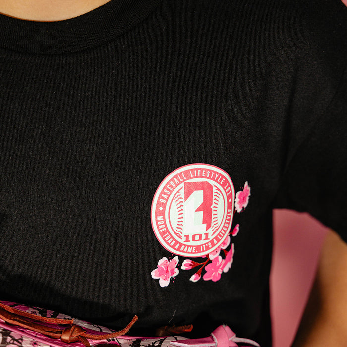 Close up of the pink cherry blossom BL101 seal logo on the chest of a black tee