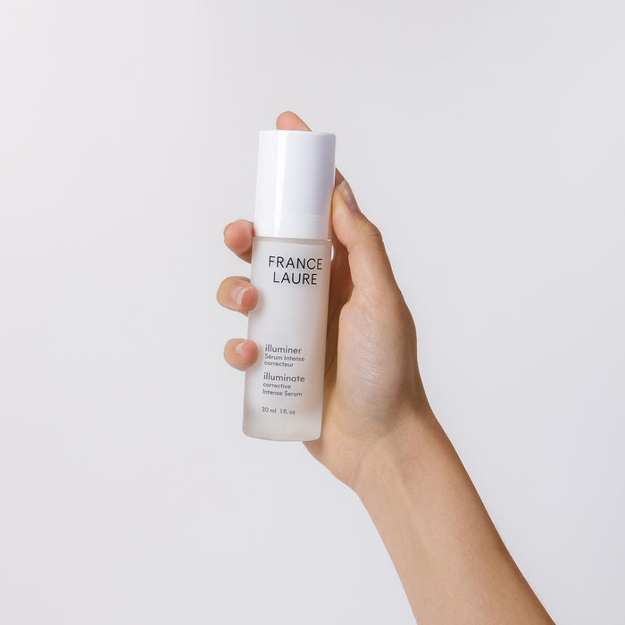 Hand holding France Laure Illuminate Corrective Intense Serum 30ml, a brightening skincare product for all skin types
