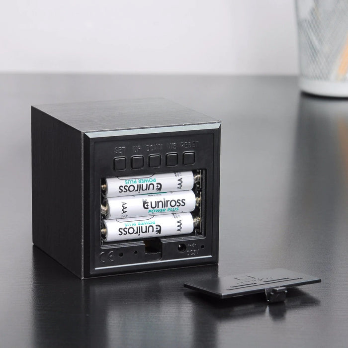 Black cube digital clock with blue LED, open battery compartment and buttons