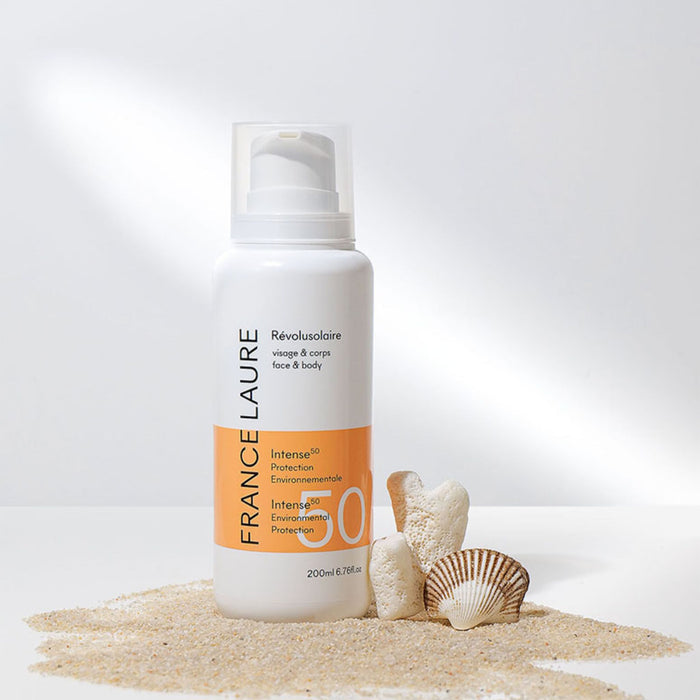 France Laure Révolusolaire SPF 50 face & body sunscreen bottle with sand and seashells, offering intense environmental protection