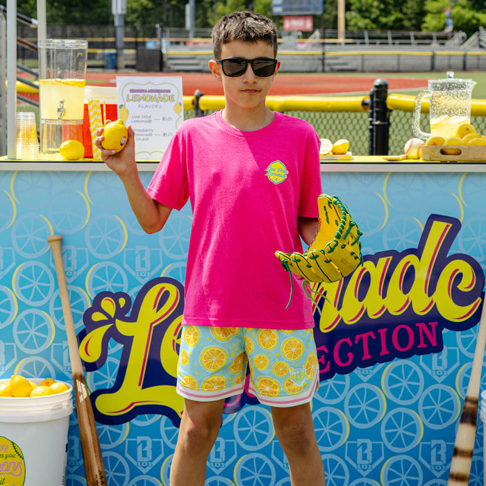 Youth model wearing pink youth graphic tee with "Electric Lemonade" design