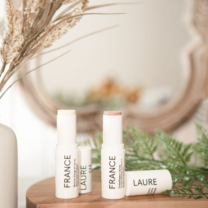 France Laure radiant lip balm and face & lip balm tubes displayed on wood with dried flowers, showcasing natural skincare for all skin types