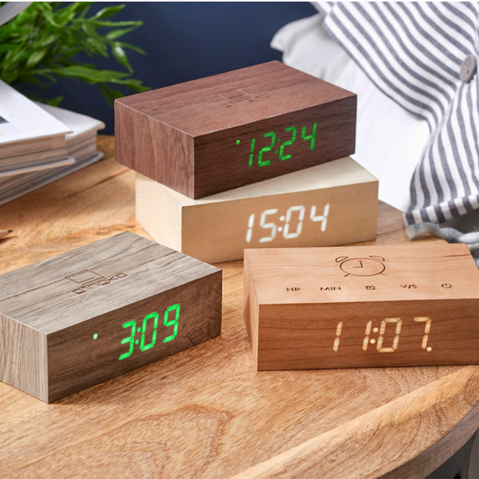 Wooden Flip Click Clock blocks with green LED times stacked on a desk surface