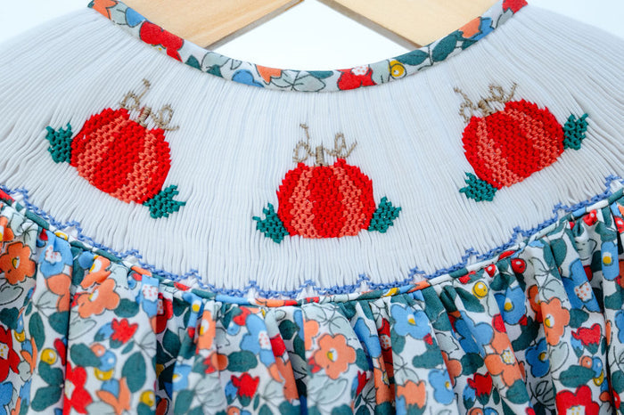Close-up of smocked pumpkin embroidery detail on Ruth and Ralph blue floral Bloomer Set