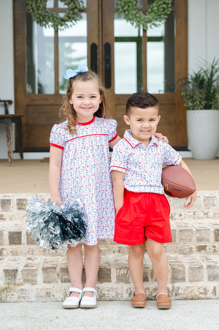 Little boy's game day polo set featuring footballs and tailgate motif print with red piping, paired with red shorts