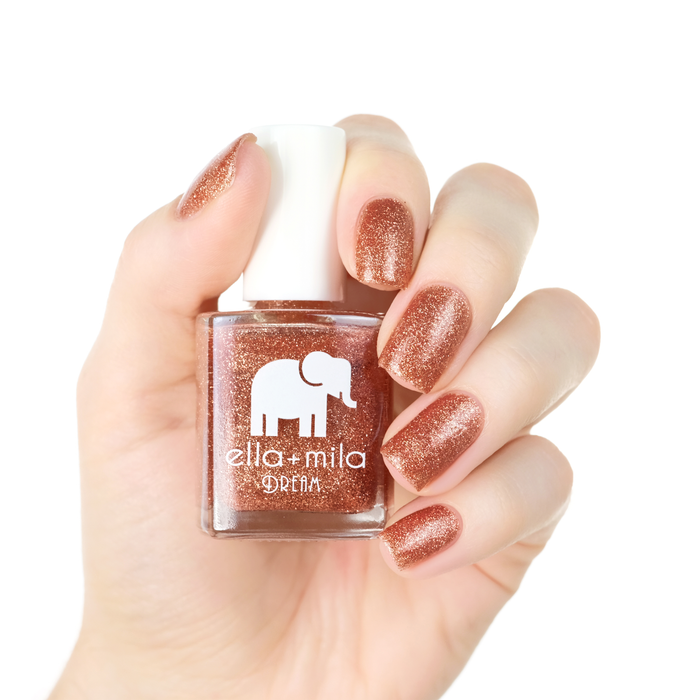 Glow With Me bronze and gold glitter nail polish manicure on a light skin tone with the bottle