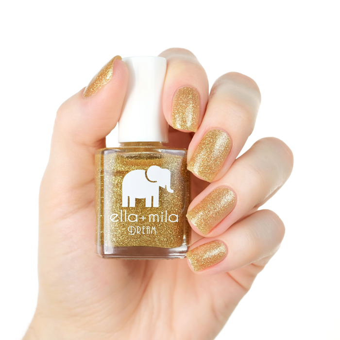 Golden Fairy gold glitter nail polish on a light skin tone, hand holding the bottle