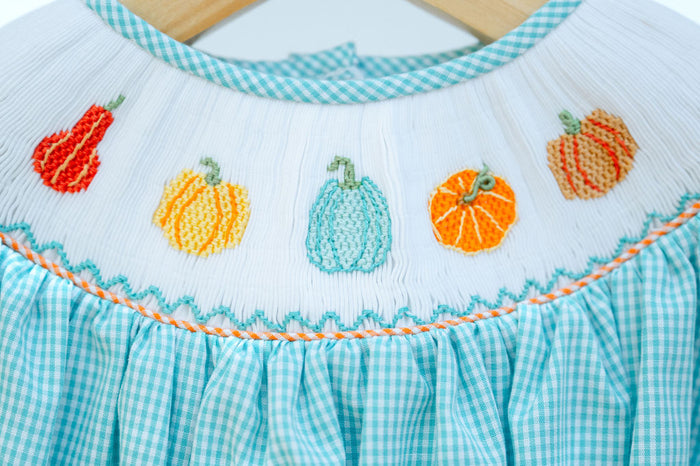 Close-up of smocked fall gourds embroidery detail on teal gingham Bubble, featuring pumpkin and gourd designs