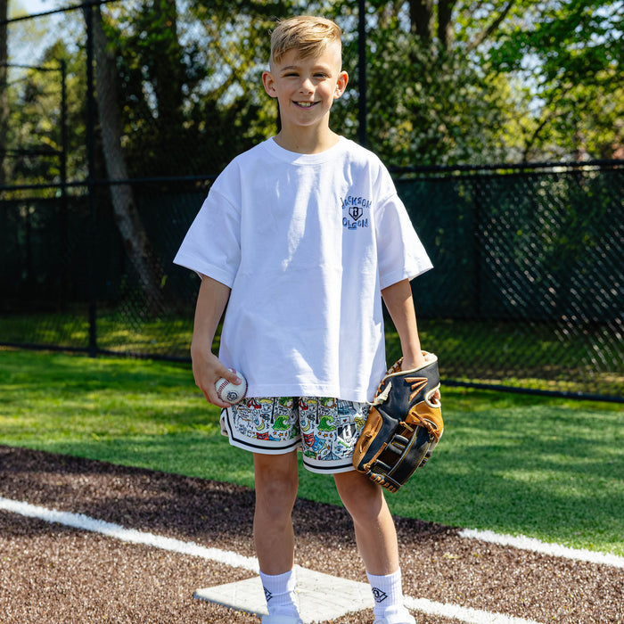 Youth player standing on a base holding a ball and glove, wearing the white Jackson Olson x BL101 relaxed tee with chest logo