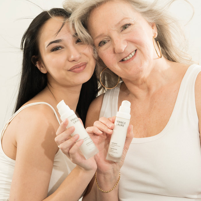 Two women holding France Laure skincare bottles — hydrate and regenerate creams for all skin types and ages
