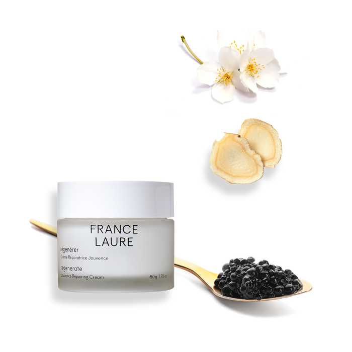 France Laure Regenerate Jouvenance Repairing Cream jar with white flowers, ginseng slices, and black caviar on gold spoon against white background