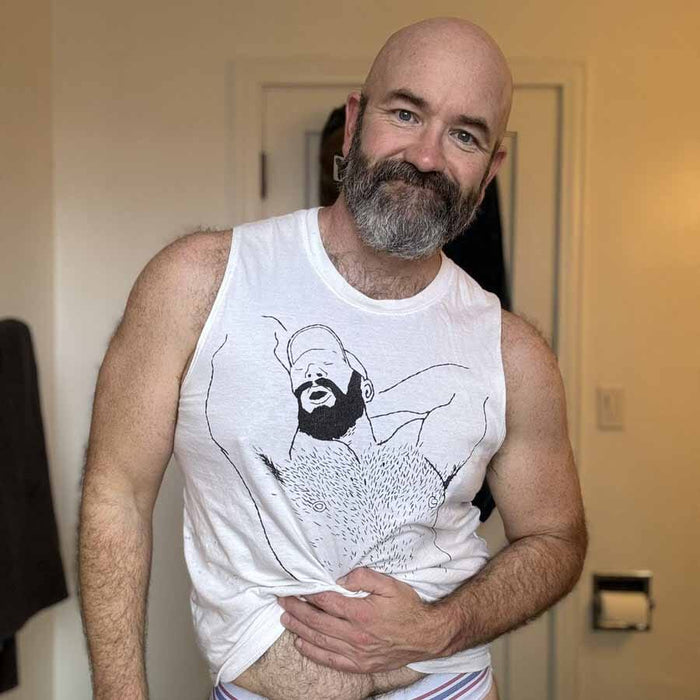 Man wearing a white tank top with a graphic design, standing indoors.