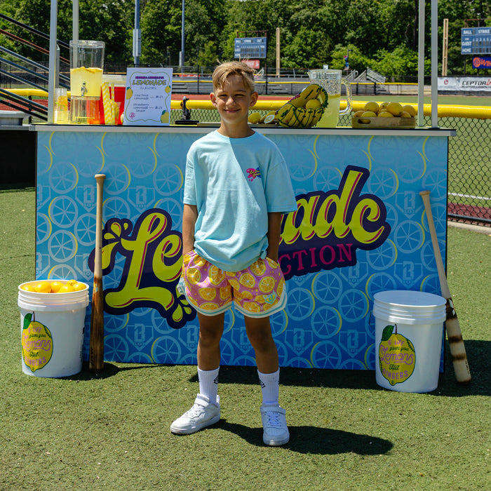 Youth model wearing blue youth graphic tee with "Lemon Burst" design