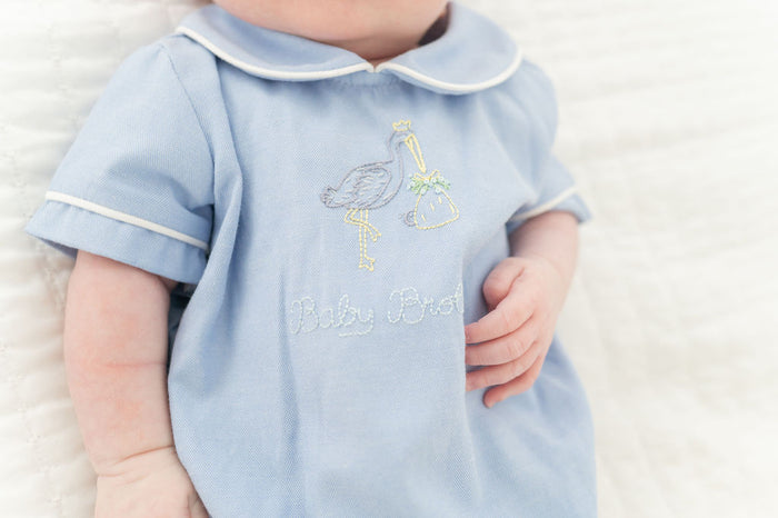 Up close image of baby brother text and stork embroidery.
