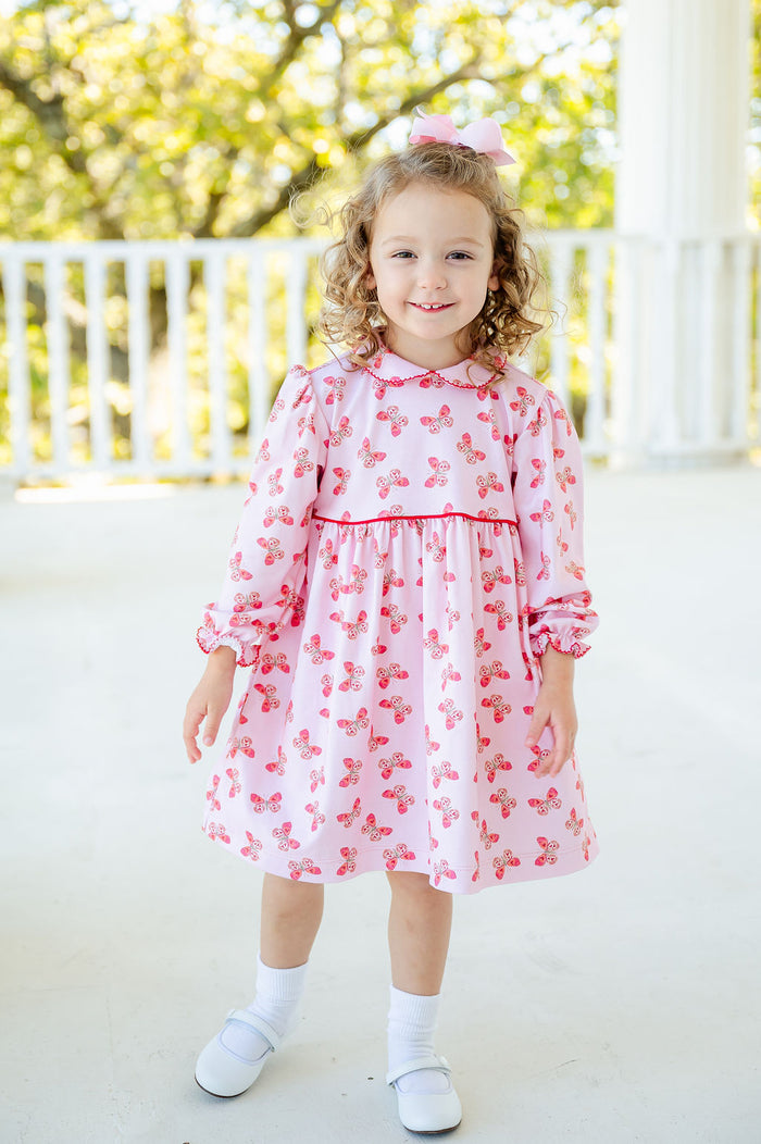 A little girl in the Butterfly Heart Dress, her outfit full of playful butterflies and sweet details.
