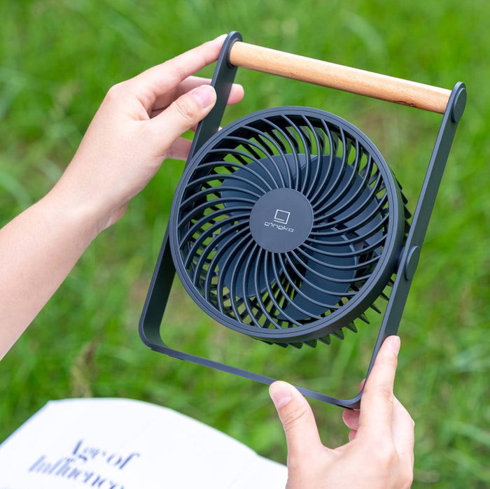 Portable dark fan with wooden handle, circular grille and frame held in hands
