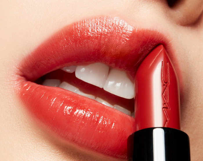 M.A.C LustreGlass sheer-shine lipstick in Chili Popper, showing the vibrant coral-red lipstick tube with the product label.