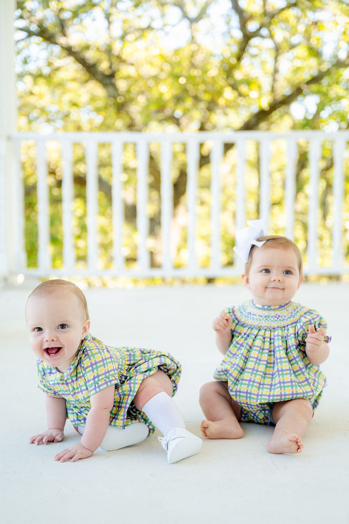 Dressed in the smocked Mardi Gras bubble, a baby girl is ready to join the fun of parades and parties.