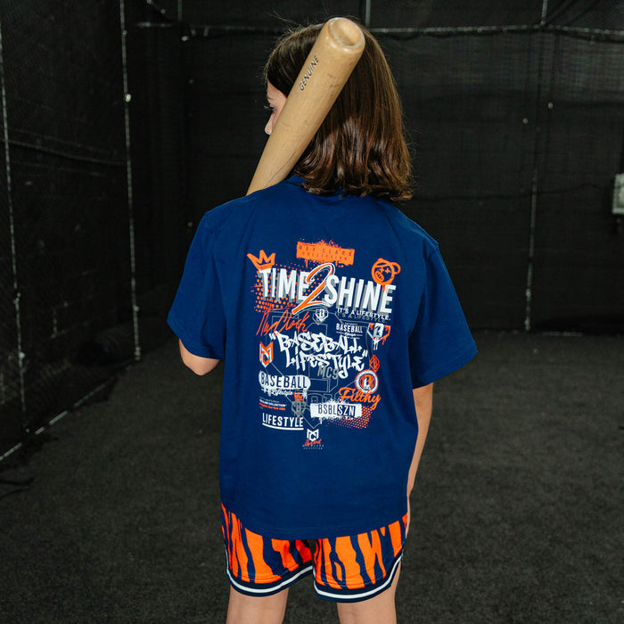 Person wearing a blue t-shirt with text and graphics, holding a baseball bat, in an indoor setting.