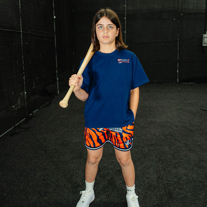 Person wearing a blue t-shirt and orange shorts with a bat in an indoor setting