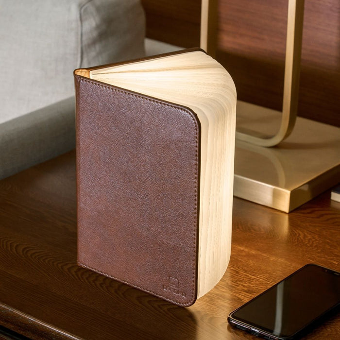 Brown leather smart booklight with hinged cover, illuminated pages fanned at angle