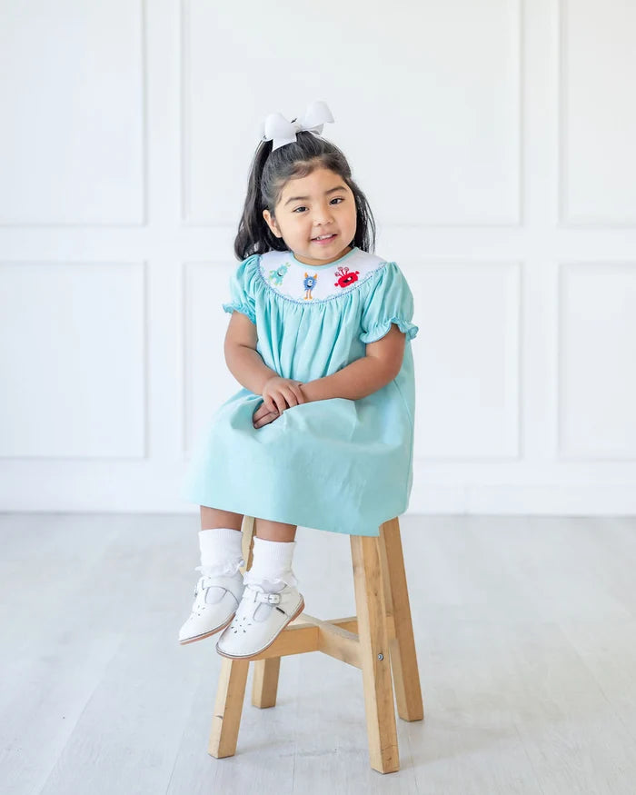 GIRL WEARING SMOCKED MONSTERS DRESS
